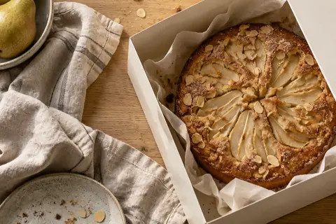 Generated pear and almond cake at a bakery packing station.